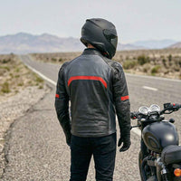 A person in a black leather jacket and helmet standing next to a motorcycle.