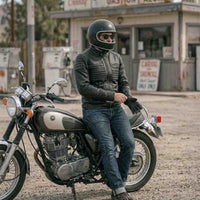 Person sitting on a motorcycle in front of an old gas station.