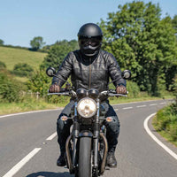 Person riding a motorcycle on a road in RIDERACT touring jacket